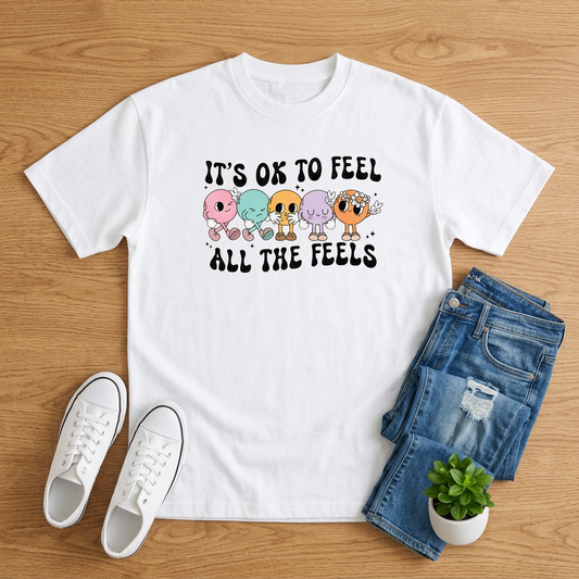 White All the Feels pastel skeleton T-shirt with jeans and white sneakers on brown wood
