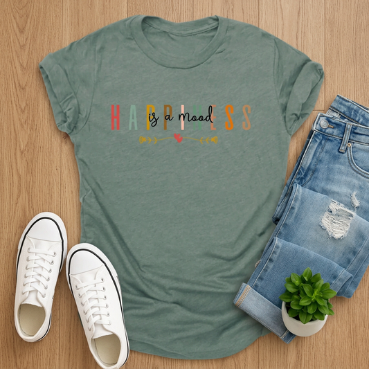 Sage-green Happiness Is a Mood T-shirt styled with jeans and white sneakers on brown wood