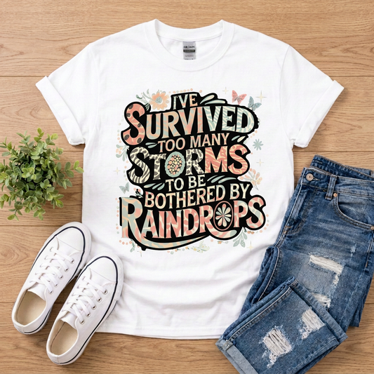 White I’ve Survived Too Many Storms T-shirt with jeans and white sneakers on brown wood