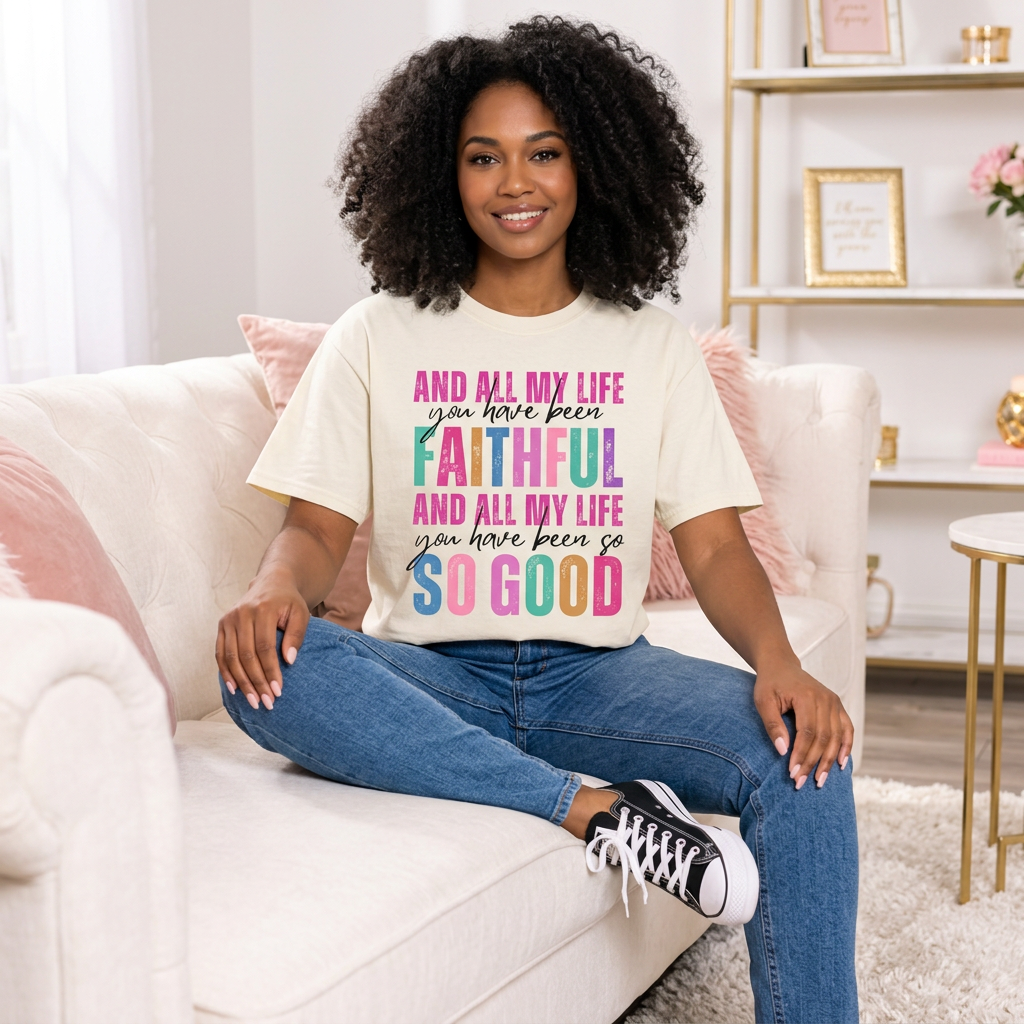 Seated model wearing cream All My Life You Have Been Faithful graphic T-shirt with jeans and black sneakers